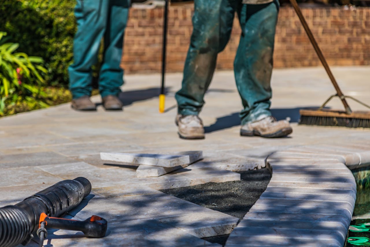 creative-01 Workers laying tiles on an outdoor patio under sunlight.